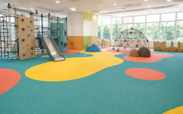 Indoor play centre climbing wall standing on bright multicoloured rubber surfacing.